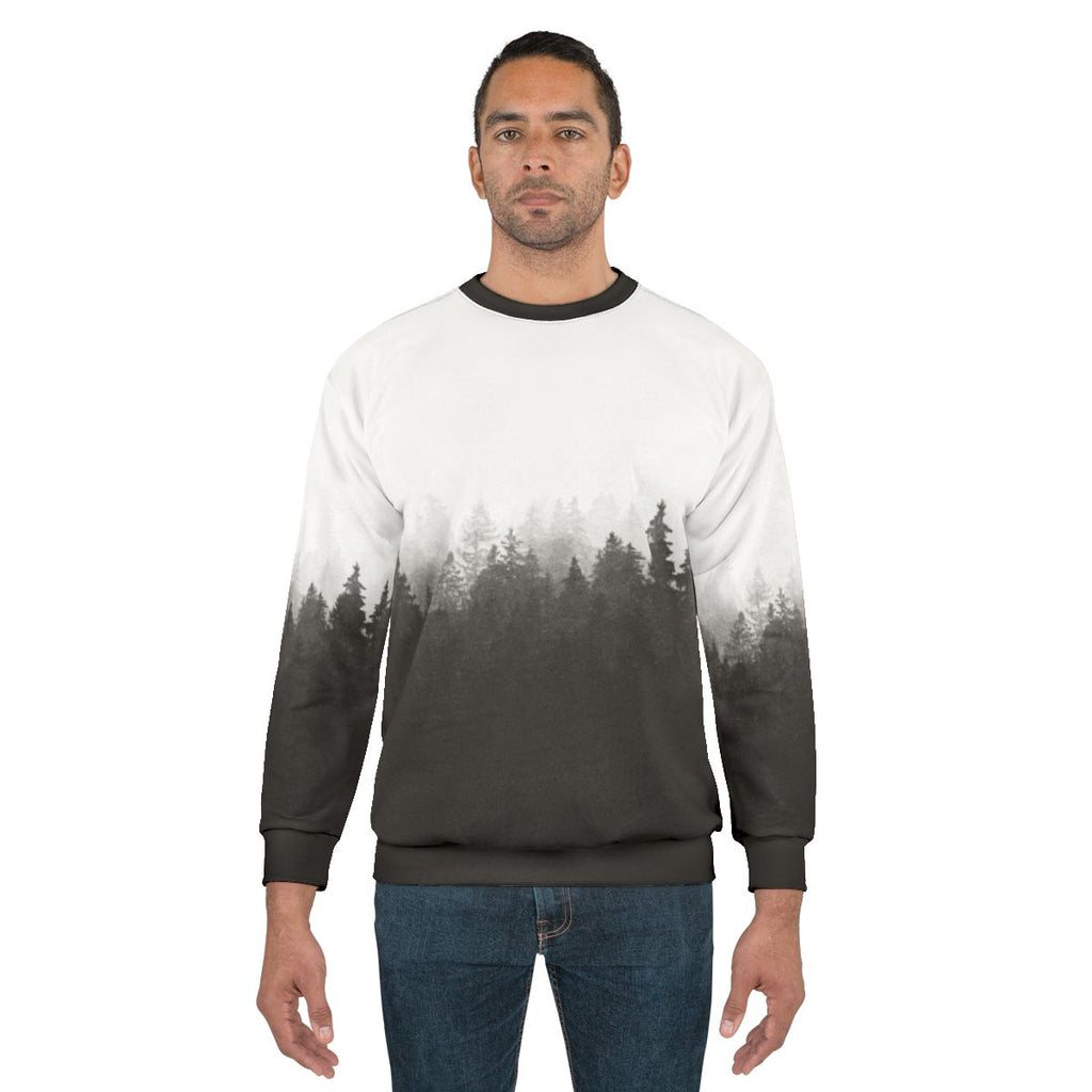 A person hiking in a foggy, forested landscape wearing a nature-inspired sweatshirt