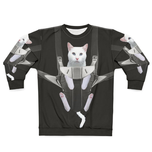 Tabby cat snuggling in a baby carrier on a white sweatshirt