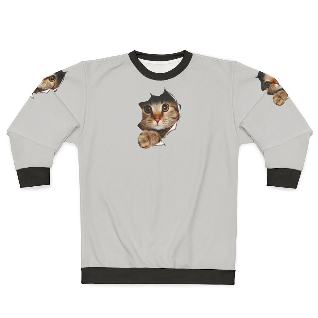 Funny cat peeping out from a torn sweatshirt