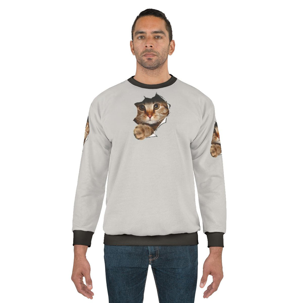 Funny cat peeping out from a torn sweatshirt
