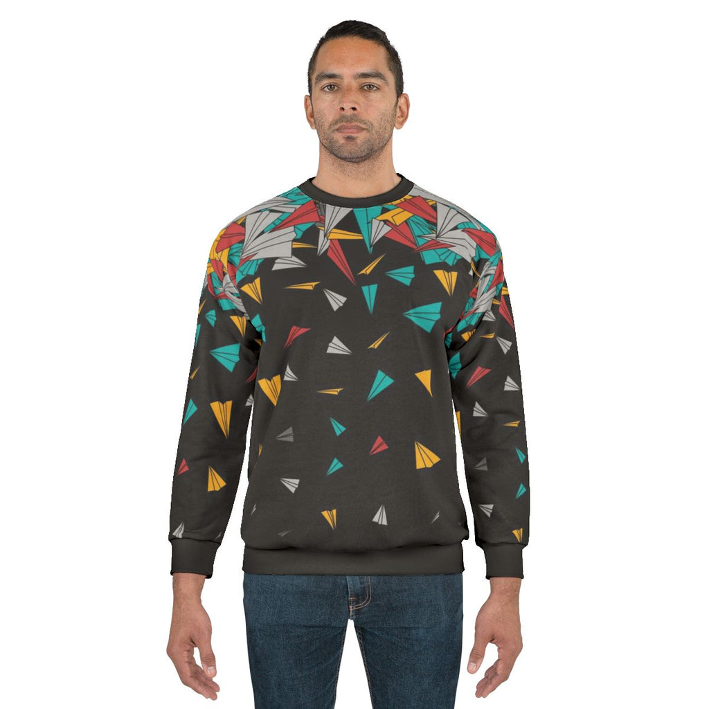 Geometric paper plane design on a colorful sweatshirt