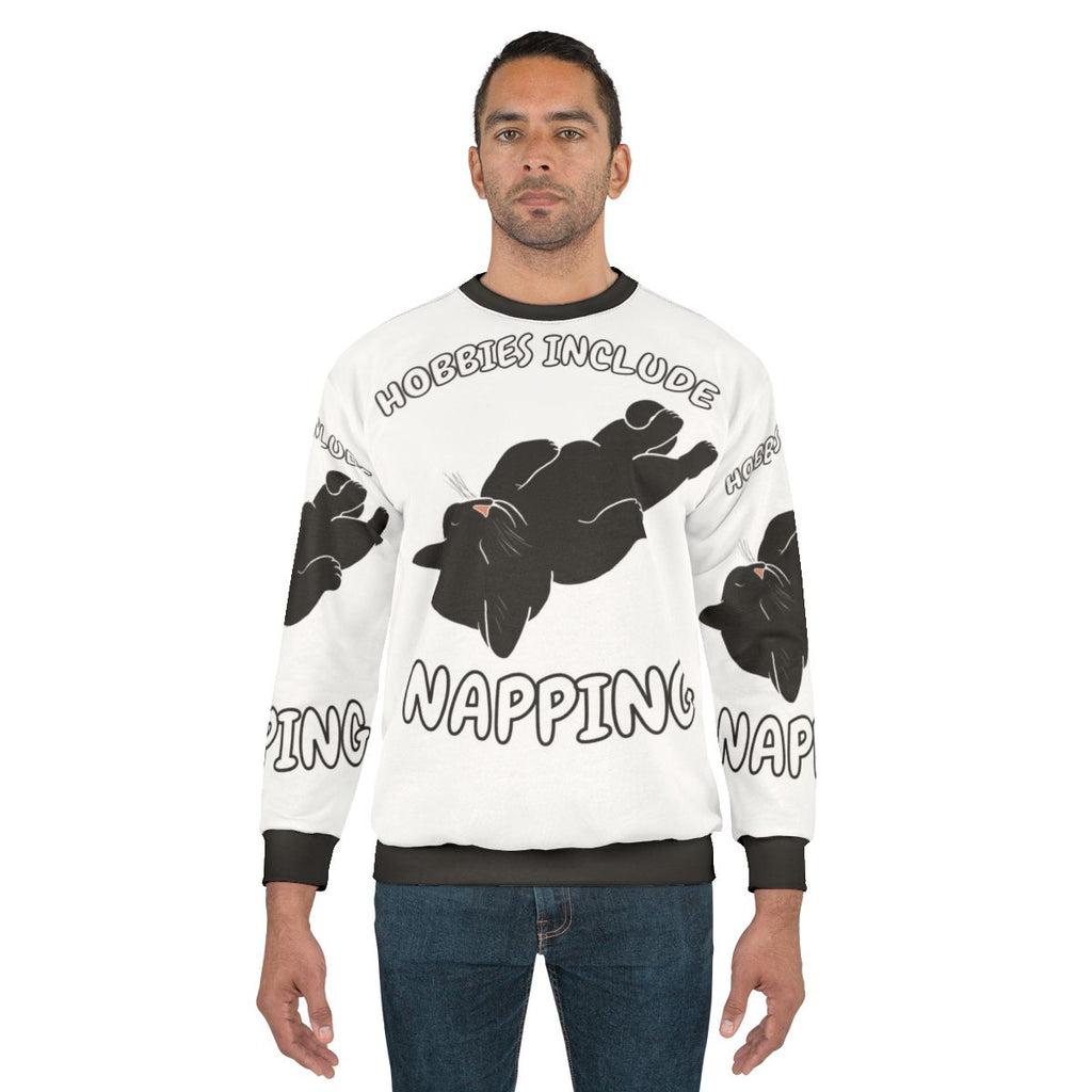 A black cat sweatshirt with the text "Hobbies Include Napping"