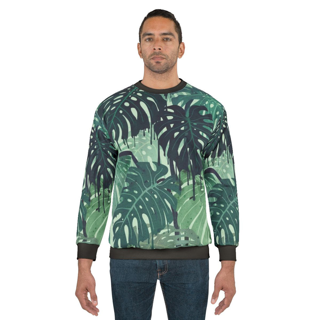 Tropical monstera leaves melting in a surreal green and blue sweatshirt design