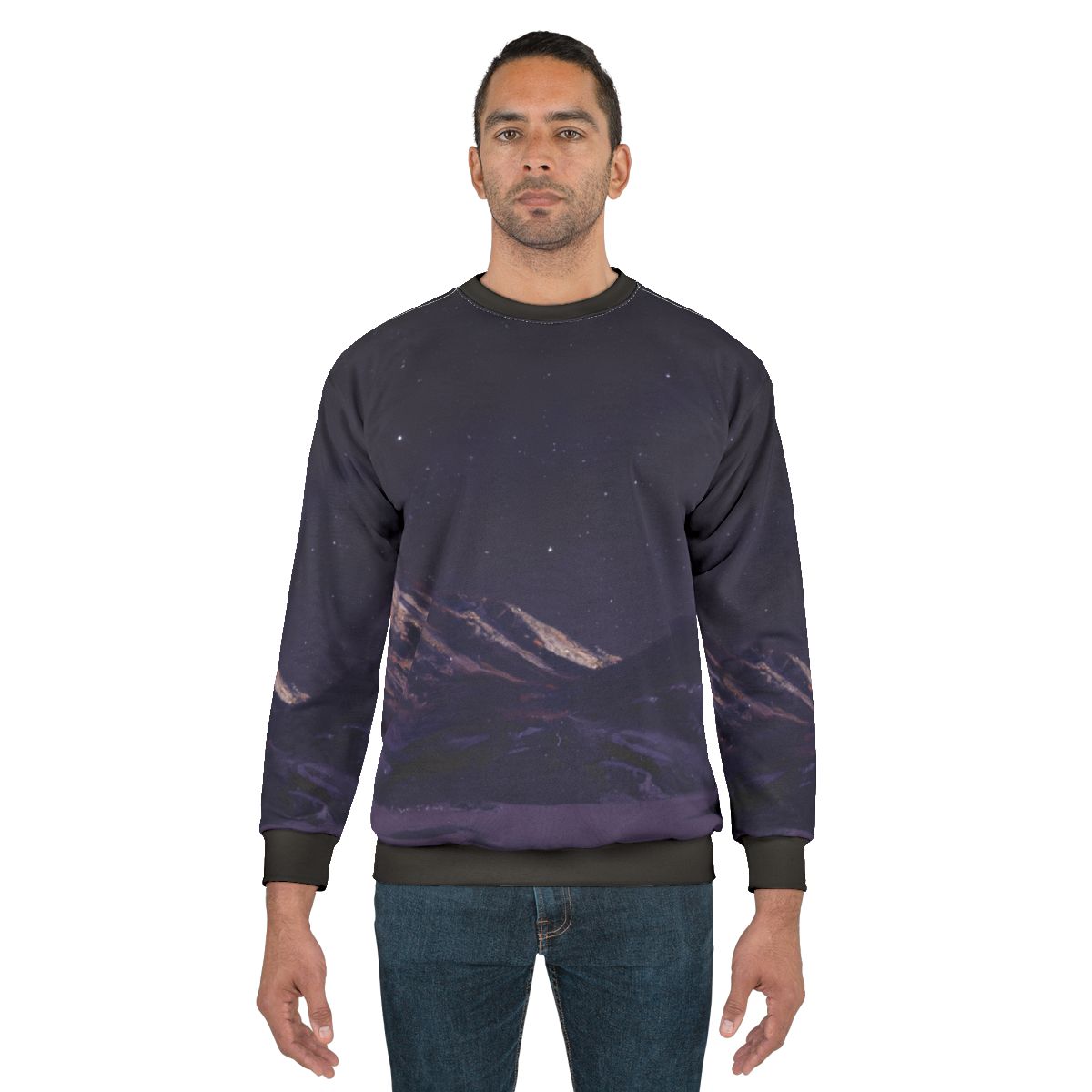 A person wearing a sweatshirt featuring a design of mountains against a night sky filled with stars.
