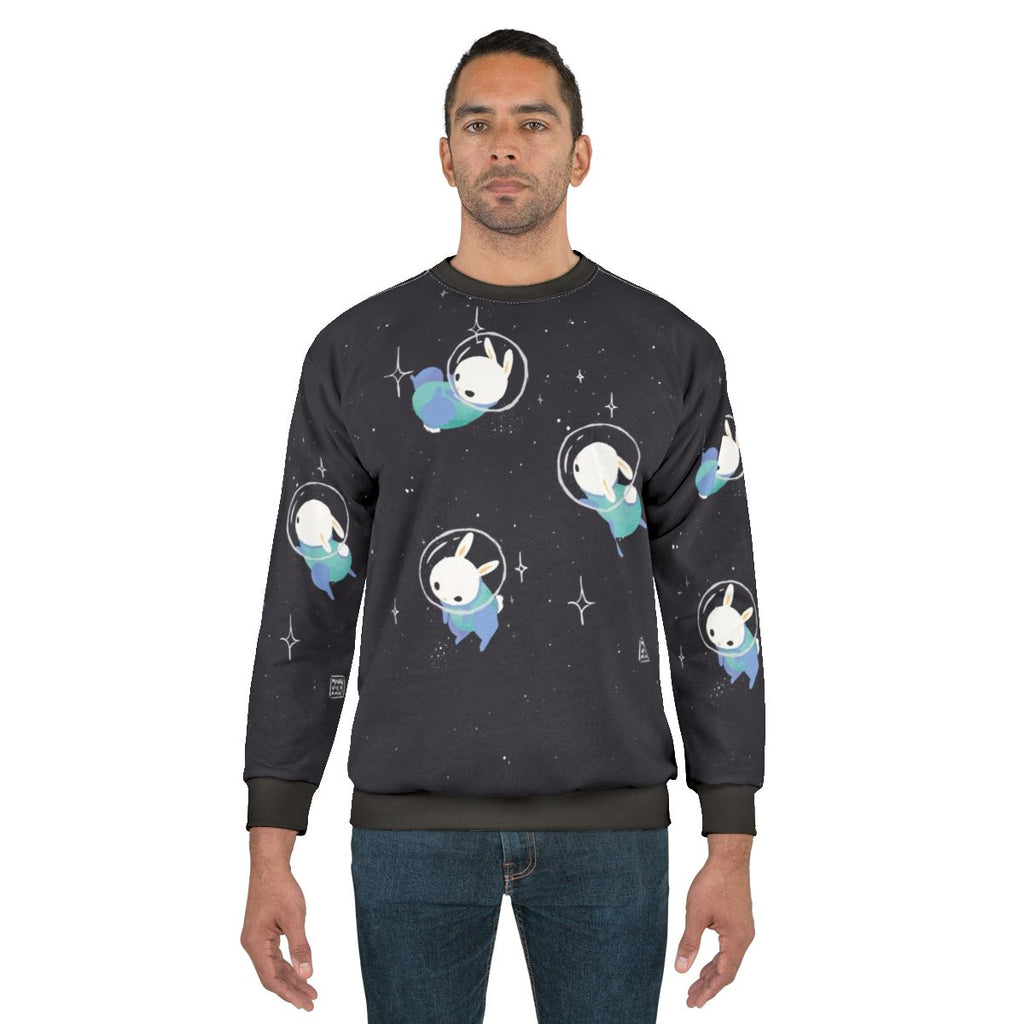 A cute and cozy sweatshirt featuring digital illustrations of adorable space bunnies and rabbits exploring the cosmos