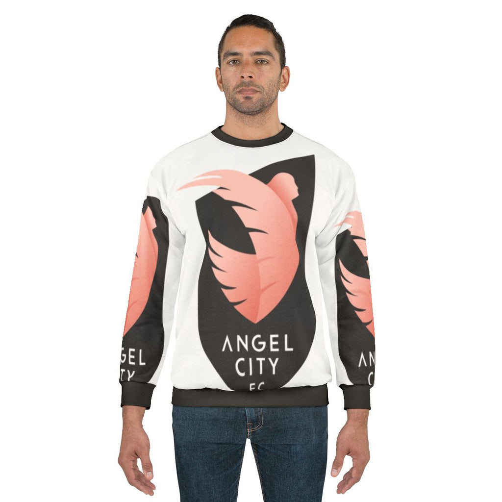 Woman wearing an Angel City Soccer sweatshirt with a football design
