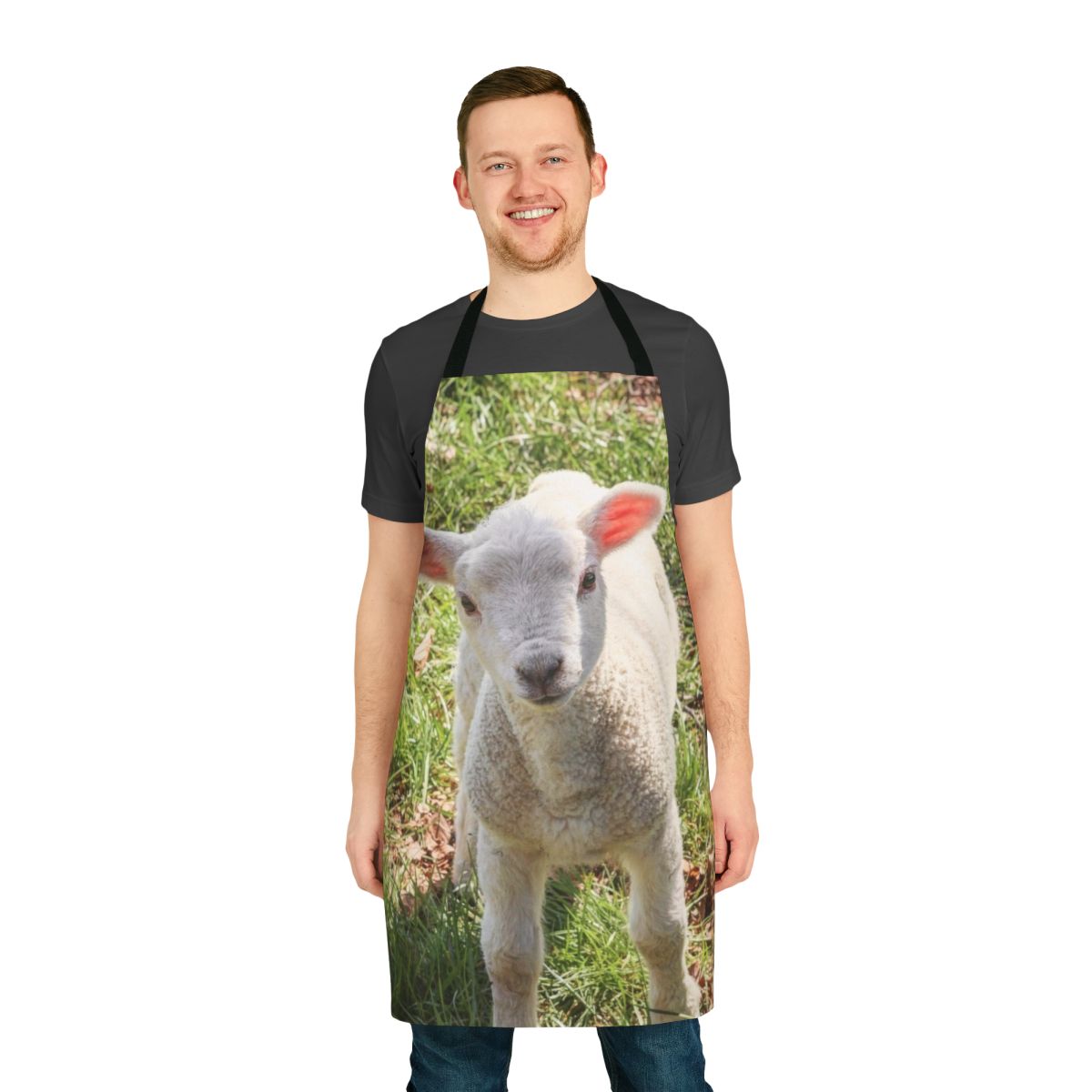 A close-up photo of a cute, young baby lamb standing in a grassy, pastoral setting.