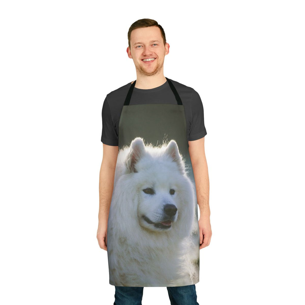 A white fluffy Samoyed dog wearing an apron with a smiling expression