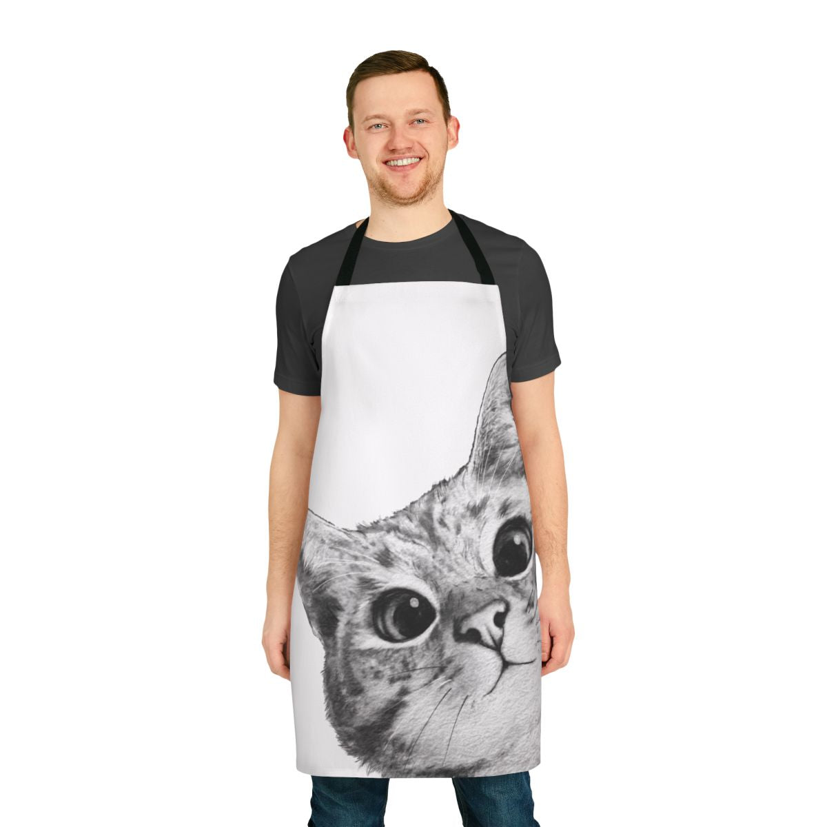 A black and white cat peeking out from behind a funny cat-themed kitchen apron