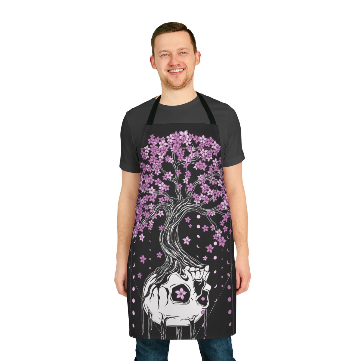 A black apron with a skull and cherry blossom design, a gothic and macabre style perfect for the kitchen.