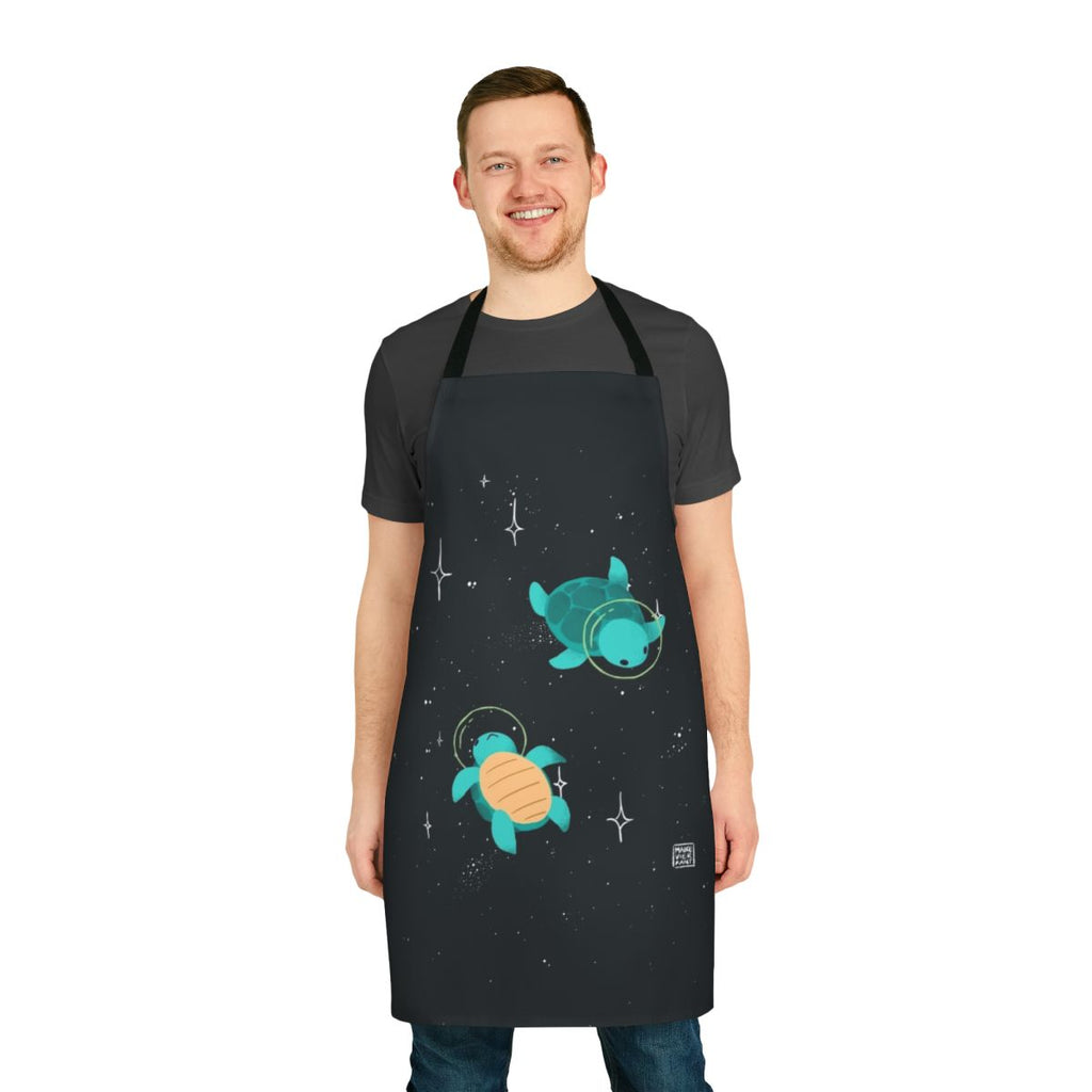 Apron featuring a design of a cute, green space turtle exploring the galaxy with stars and planets in the background.