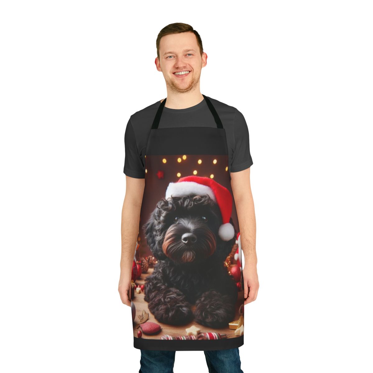 A black cockapoo dog wearing a Santa hat on a Christmas-themed apron