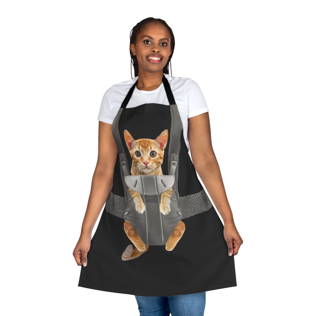 Image of an orange cat sitting in a baby carrier, with the text "Monty The Cat In Baby Carrier Apron"