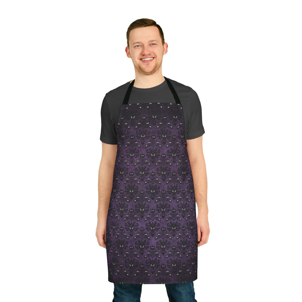 A black and purple apron with a haunted mansion wallpaper design, perfect for spooky kitchen tasks.