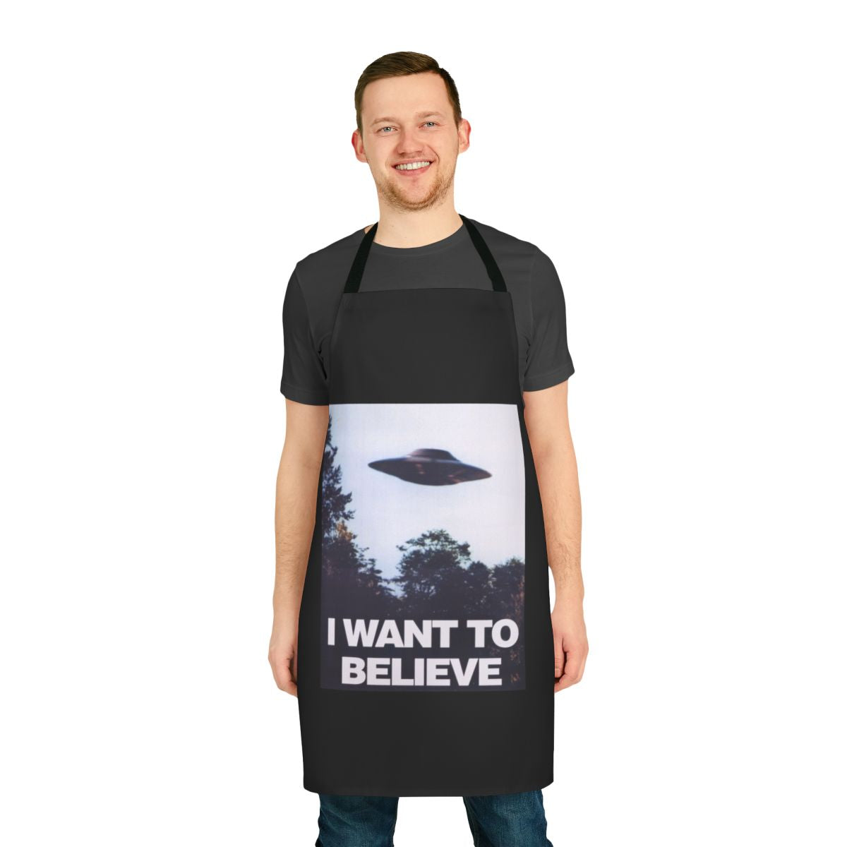 A black apron with an "I Want to Believe" graphic, featuring spooky elements like UFOs and aliens.