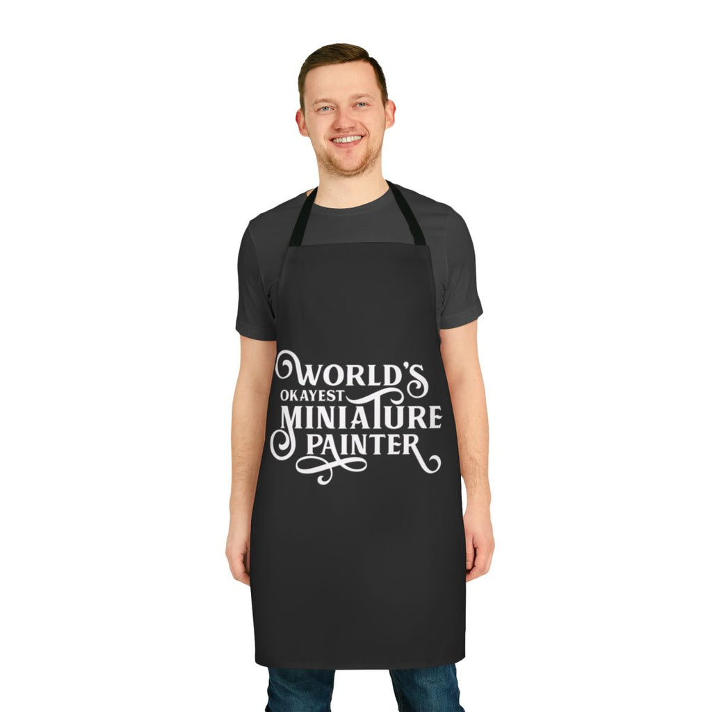 A high-quality apron featuring a "World's Okayest Miniature Painter" design, perfect for tabletop gamers and miniature enthusiasts.
