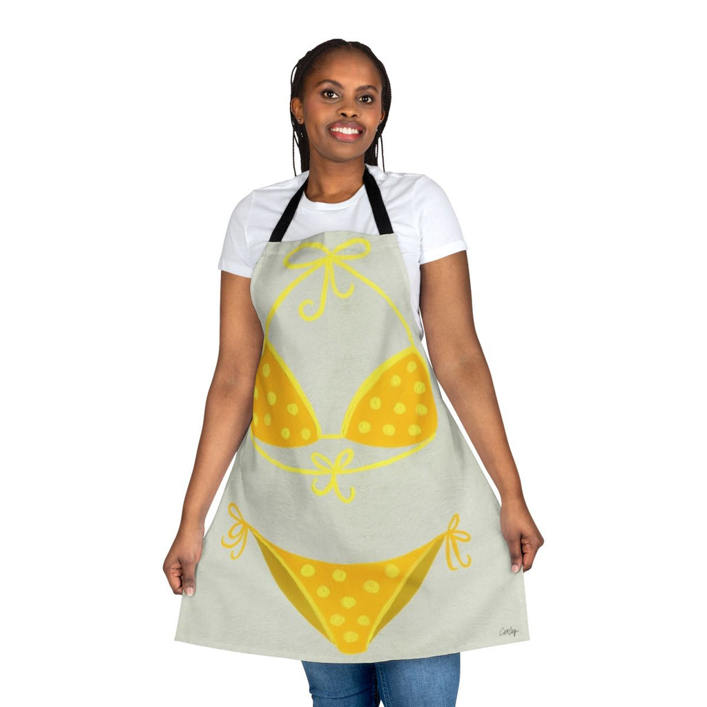 A cream-colored apron with a yellow polka dot pattern, inspired by classic swimsuit styles.