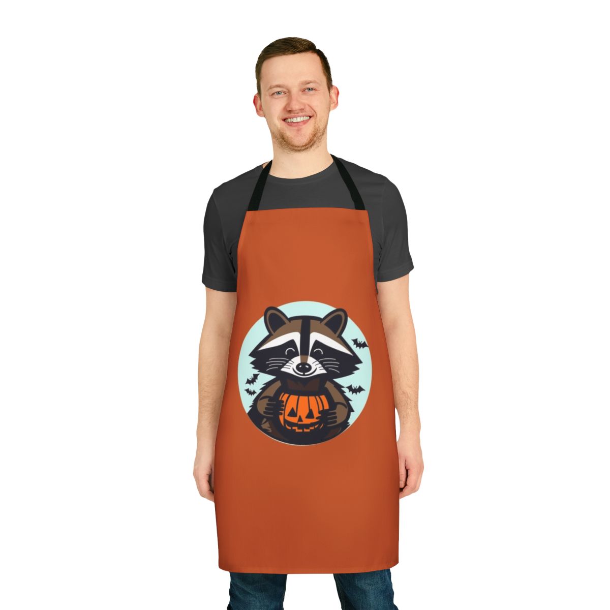 A cartoon raccoon apron with pumpkins, bats, and a jack o' lantern design, perfect for Halloween and fall festivities.