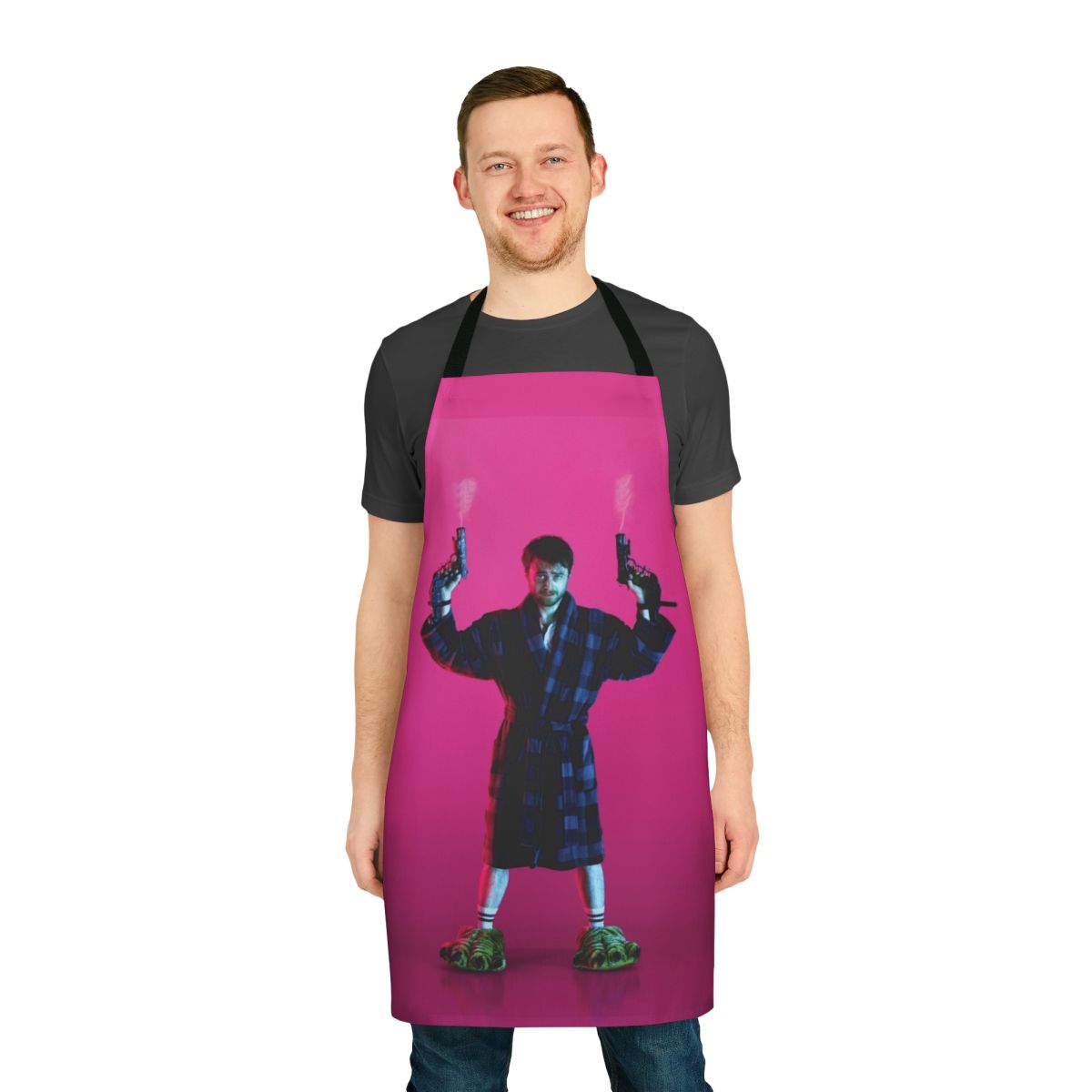 Pink apron with the text "Guns Akimbo" and a gun graphic, inspired by the movie starring Daniel Radcliffe.