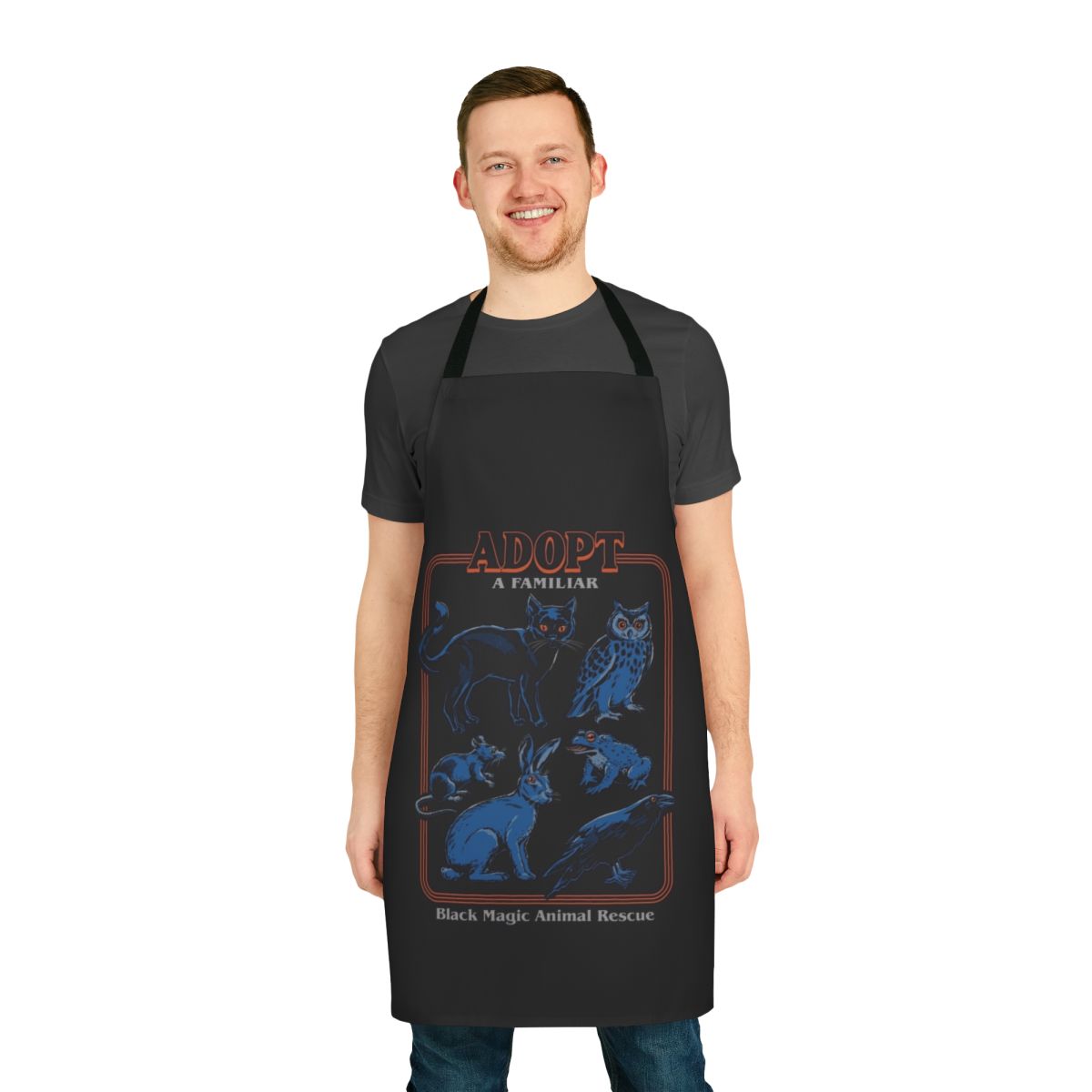 A black apron with a vintage-inspired design featuring various animals like cats, owls, crows, rats, rabbits, and toads.