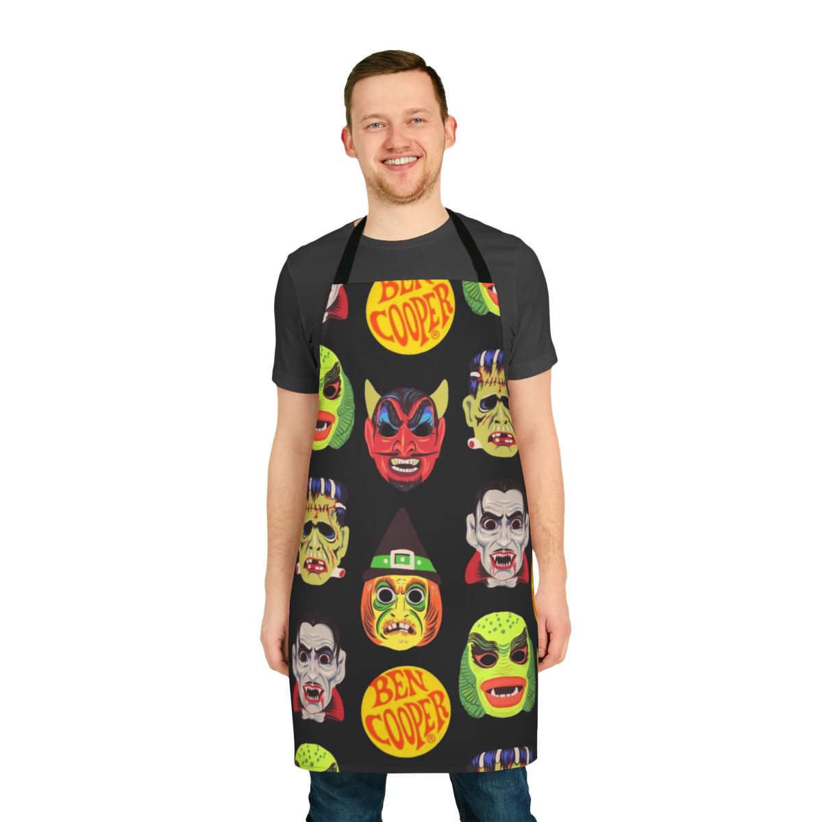 Vintage-style apron featuring classic Halloween monster masks like Dracula, Frankenstein, and the Creature from the Black Lagoon