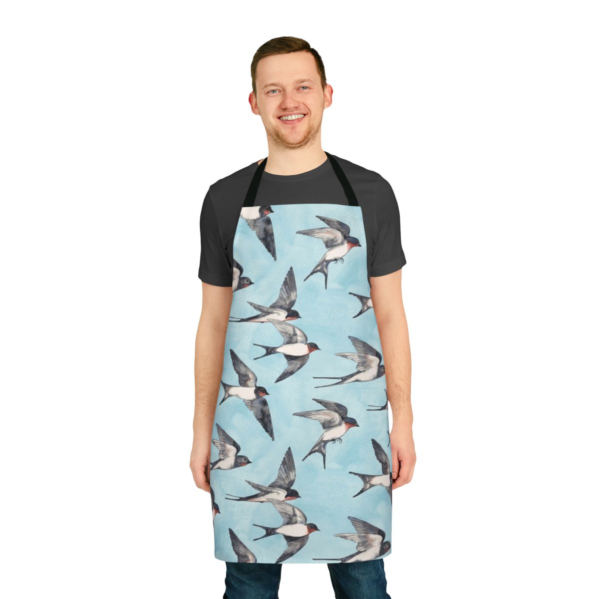 A blue and grey watercolor apron featuring a pattern of flying swallows against a cloudy sky.